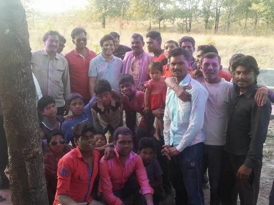 The hamlet community gathered under the trees, faces bright with Holi colours